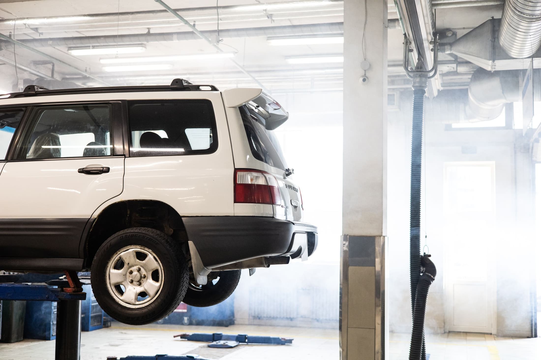 Vehicle elevated on a hydraulic lift in a clean, modern service bay