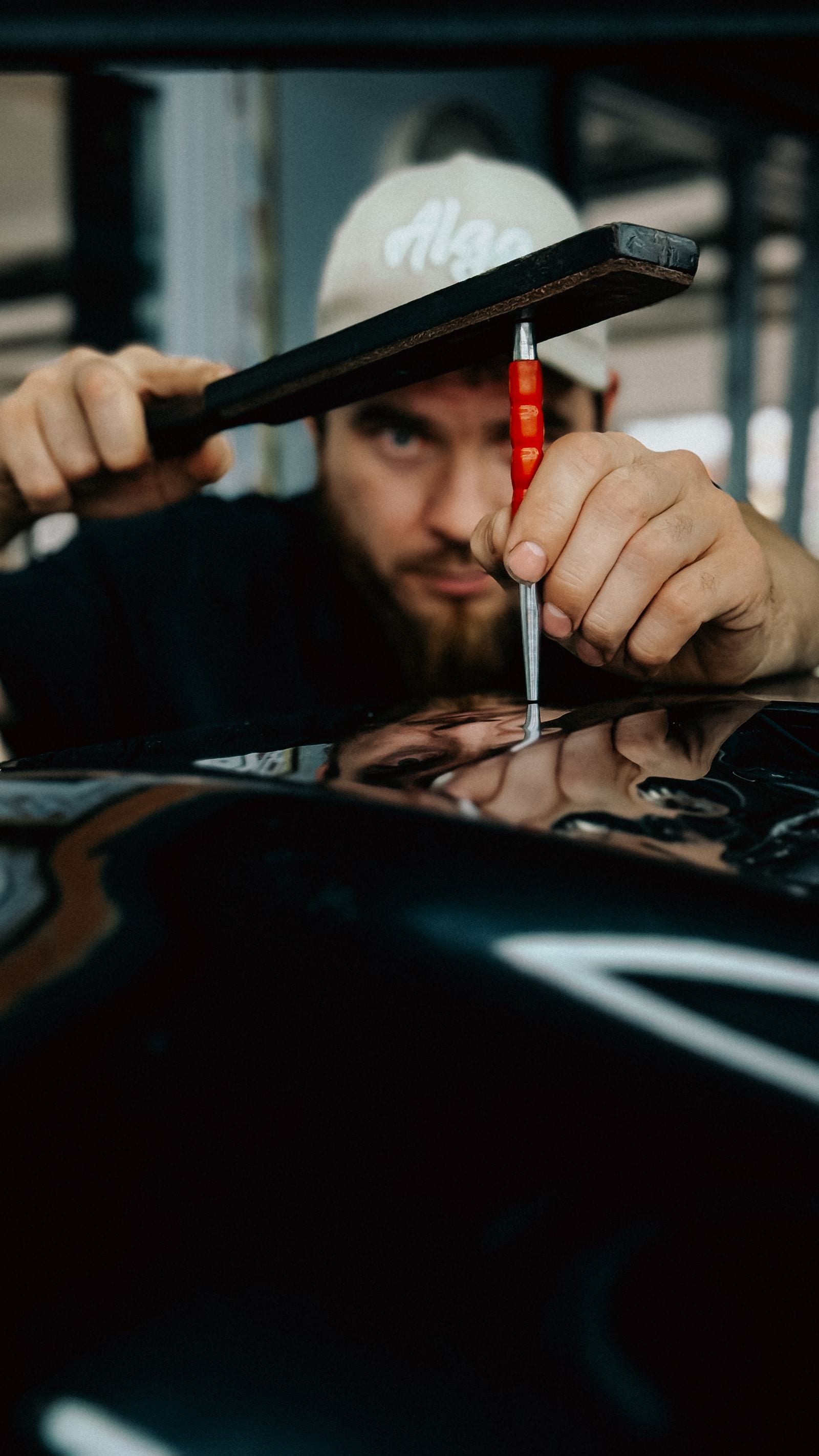 Technician panel-beating a damaged vehicle body panel