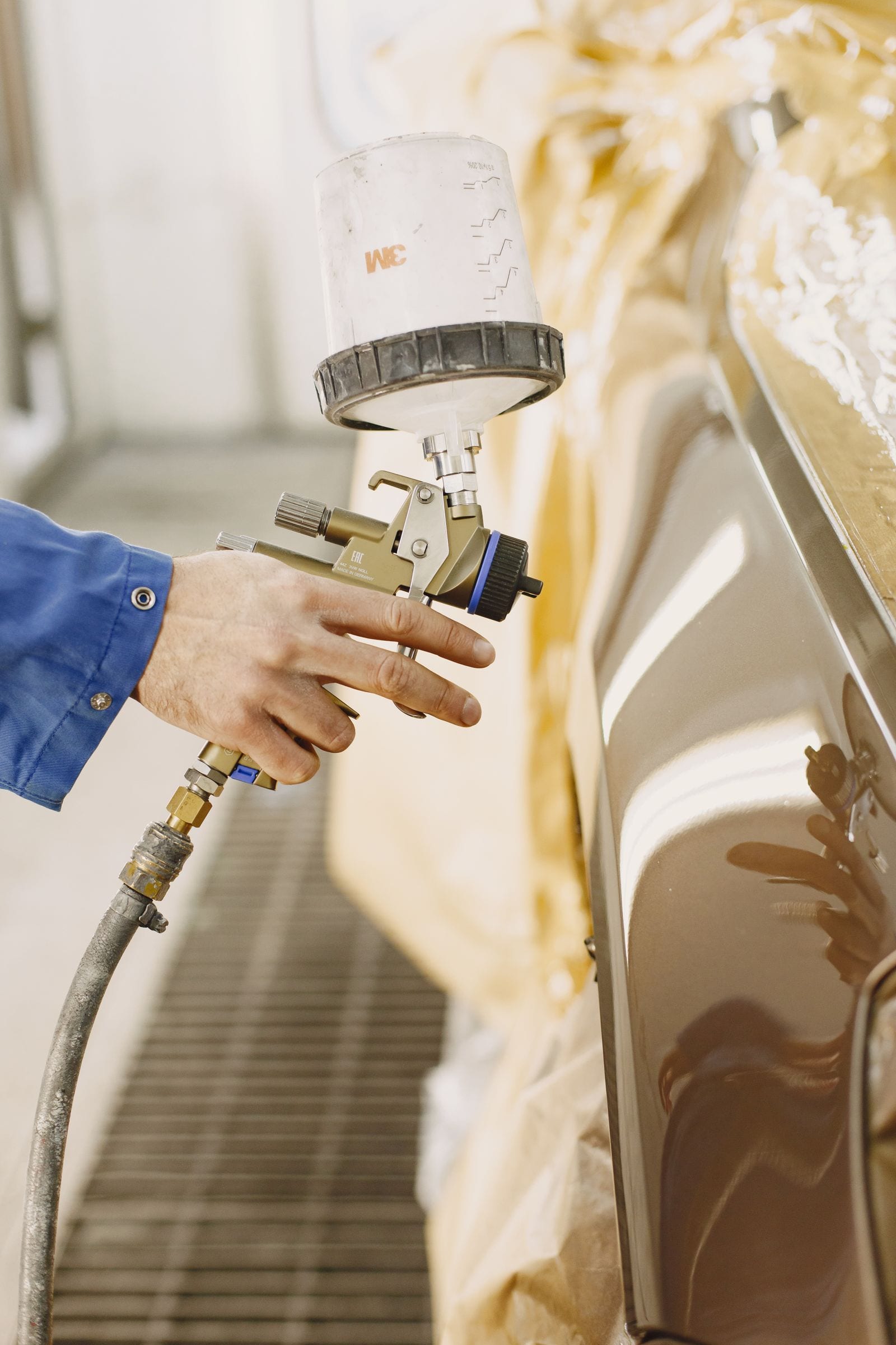Technician spray-painting a repaired vehicle panel